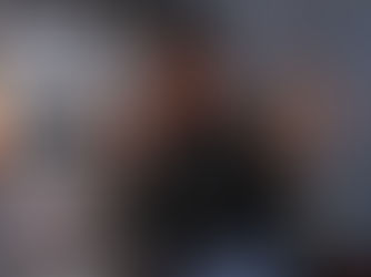 WMN Alumn DJ SLID3 poses in a recording studio poses with a peace sign. 