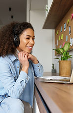 Smiling young african american teen girl wear headphones video calling on laptop. Happy mi
