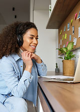 Smiling young african american teen girl wear headphones video calling on laptop. Happy mi
