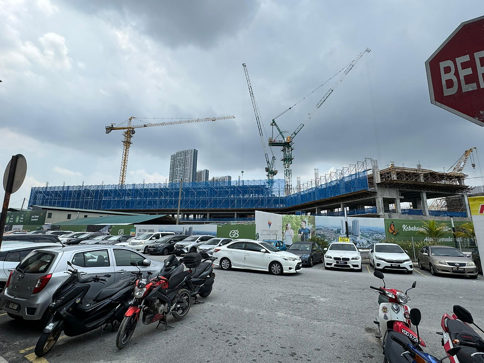 Construction progresses at Interpoint Bandar Bukit Tinggi 2, with towering cranes and a bustling site set against a cloudy sky, as vehicles are parked nearby.