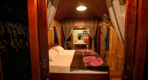 Deluxe bamboo floating room at Praiwan Raft House on Cheow Lan Lake, featuring natural wooden interiors, private bathroom, and tranquil rainforest surroundings in Khao Sok National Park.