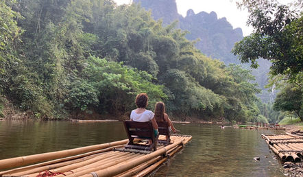 Scenic bamboo rafting experience surrounded by limestone mountains and jungle landscapes