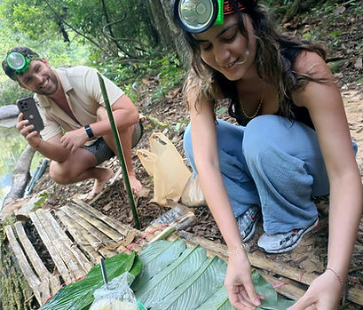 Travelers preparing traditional bamboo cooking during a rainforest expedition in Khao Sok National Park surrounded by lush tropical jungle and wilderness atmosphere.