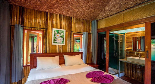 Deluxe bamboo floating room at Praiwan Raft House on Cheow Lan Lake, featuring natural wooden interiors, private bathroom, and tranquil rainforest surroundings in Khao Sok National Park.