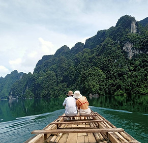 Travelers crossing the lake by bamboo raft on the way to Pakarang Cave at Cheow Lan Lake