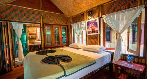 Deluxe bamboo floating room at Praiwan Raft House on Cheow Lan Lake, featuring natural wooden interiors, private bathroom, and tranquil rainforest surroundings in Khao Sok National Park.