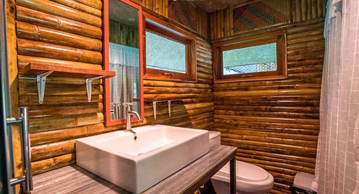 Deluxe bamboo floating room at Praiwan Raft House on Cheow Lan Lake, featuring natural wooden interiors, private bathroom, and tranquil rainforest surroundings in Khao Sok National Park.
