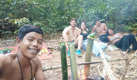 Local guides and travelers relaxing beside a forest stream during a jungle adventure in Khao Sok.