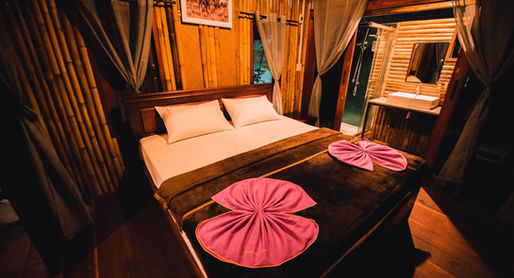 Deluxe bamboo floating room at Praiwan Raft House on Cheow Lan Lake, featuring natural wooden interiors, private bathroom, and tranquil rainforest surroundings in Khao Sok National Park.