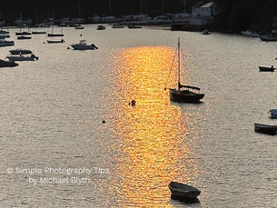 Sunset over Newton Ferrers Harbour with boats on calm water