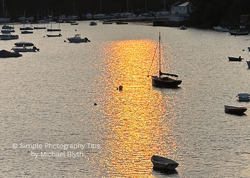 Sunset over Newton Ferrers Harbour with boats on calm water