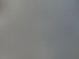 Close-up photograph of frost on a teak table, showing icy texture and dark swirling wood grain in natural morning light.