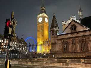 Elizabeth Tower and the London Eye at blue hour in London demonstrating warm building lighting against a cool evening sky.