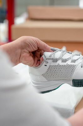 Auf dem Bild sieht man eine Kollegin, die einen Schuh im Retourenprozess prüft