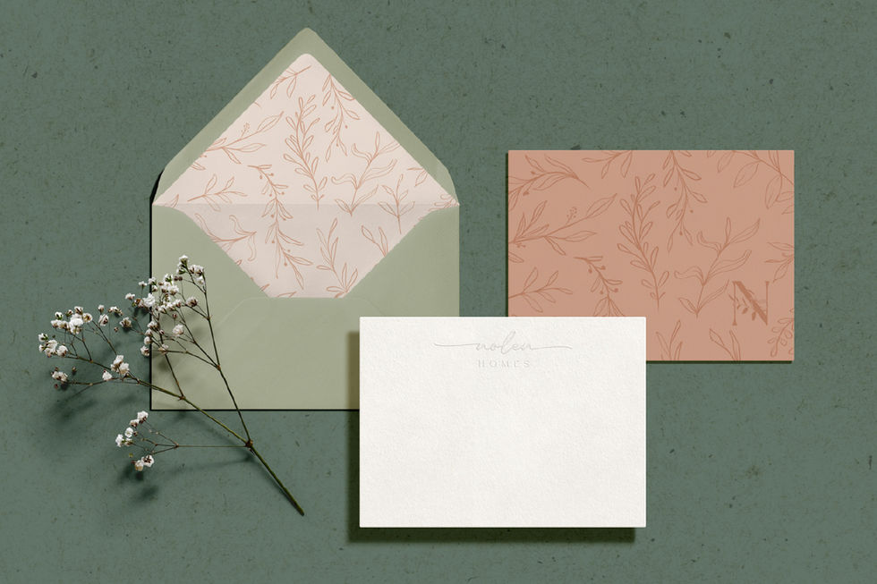 Nolen Homes stationery set featuring textured envelopes, letterpress card, and botanical accents arranged on a muted green background