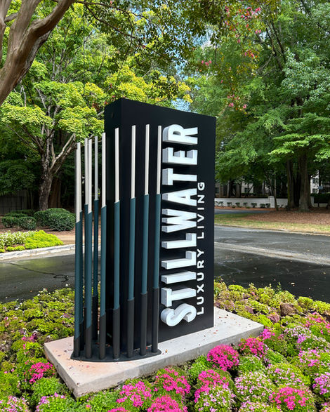 Stillwater monument sign with vertical logo design surrounded by greenery