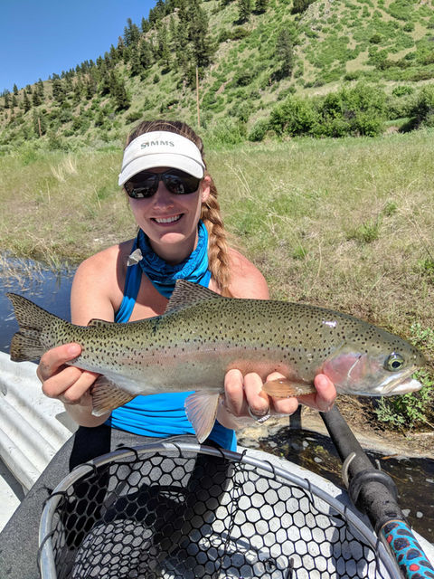 Photo of a woman holding a wild trout she caught on the river near Missoula.
