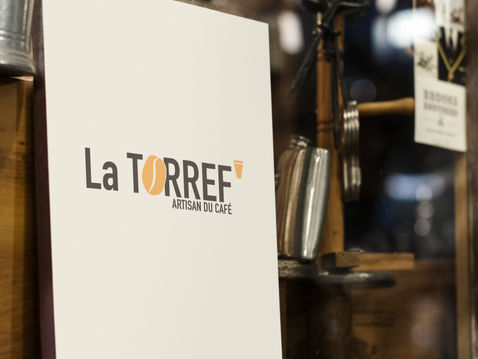 Logo de 'La Torref' en couleur sur une enseigne de vitrine, soulignant l'identité chaleureuse du café.