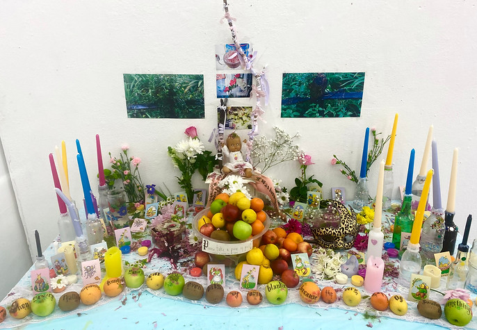 A table covered in fruit, candles and various other objects.