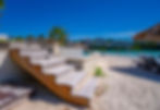Wooden stairs on a sandy beach leading to a pool