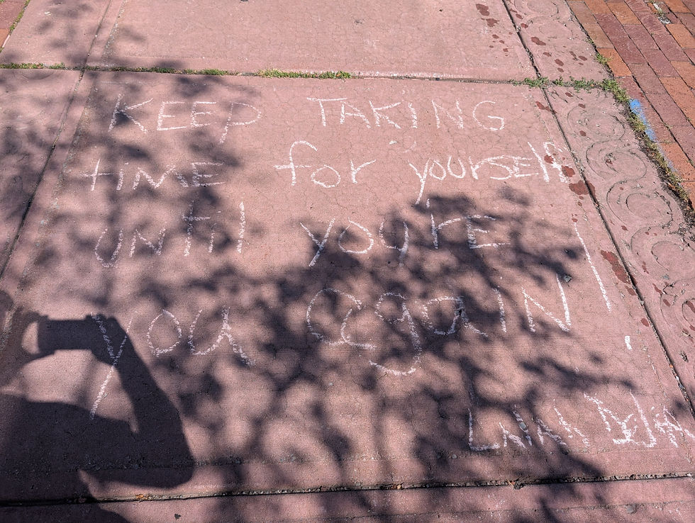 Chalk message on a sunlit sidewalk reads, "Keep taking time for yourself until you're you again!" with tree shadows across pink concrete.