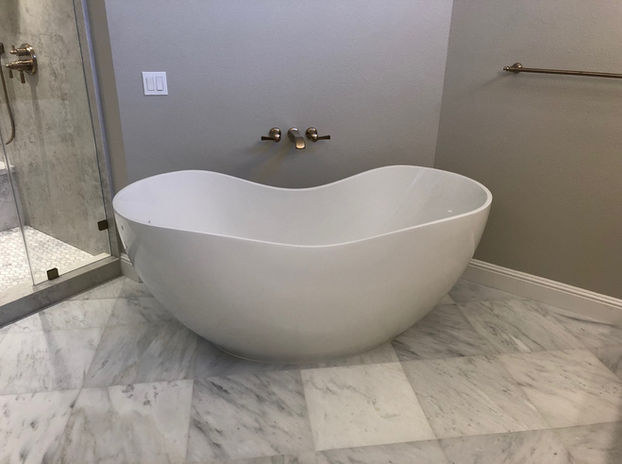Modern white bathtub in a luxury bathroom with tiled marble flooring