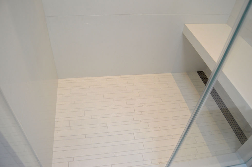 Modern white bathroom with a bench, glass shower door and tiles.