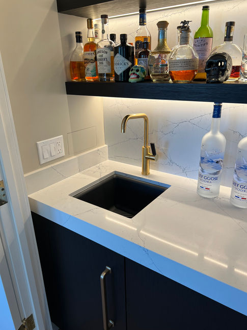 A modern bar setup with liquor bottles and gold faucet