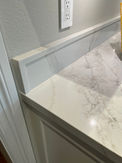 White marble countertop with light gray backsplash and a white trim design.