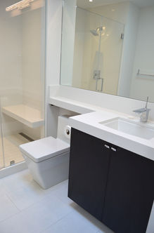 Modern white bathroom with a toilet, sink, mirror, and a glass shower.