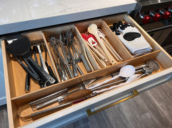 Open kitchen drawer with various cooking utensils and a heat-resistant glove.