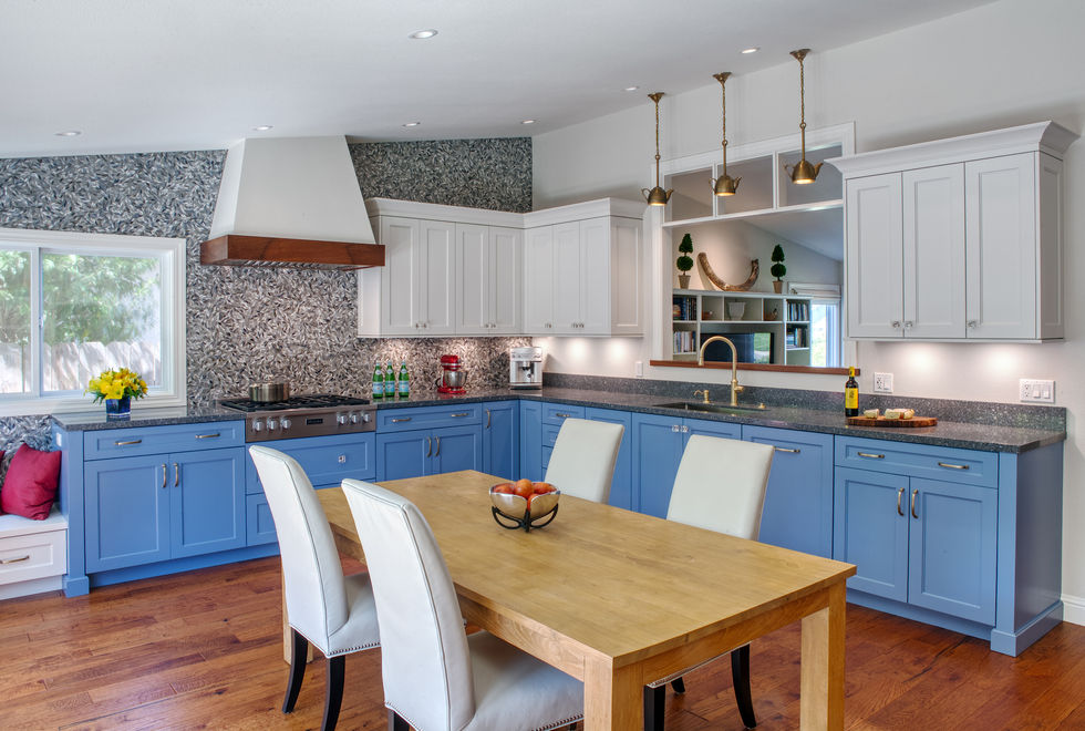 Modern kitchen design with blue cabinets, white countertops and a wooden table.