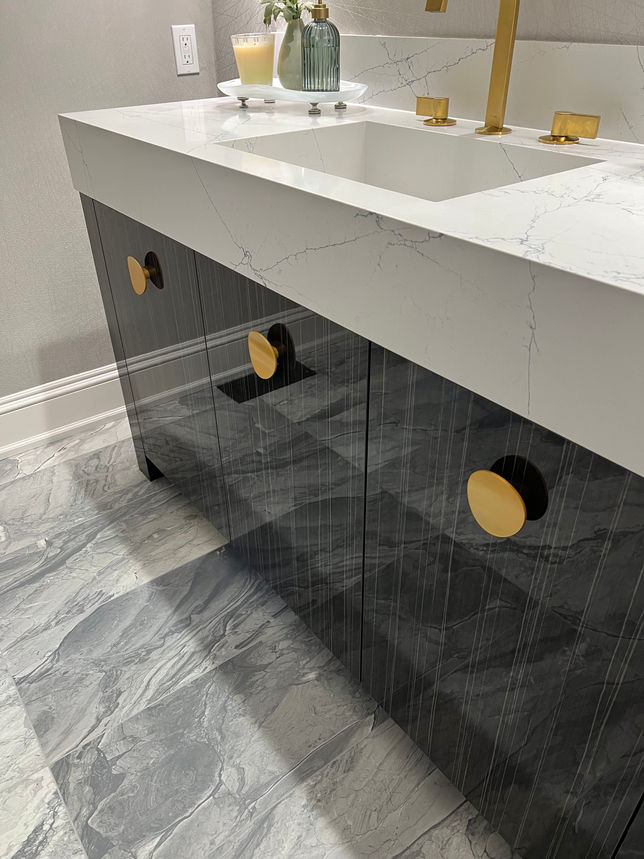 Modern bathroom vanity with black cabinets, gold hardware and marble countertop.