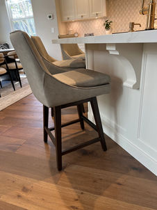 Two grey bar stools, dark wood legs sit at a white countertop.