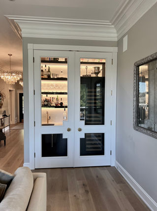 White double doors to a home bar with wine cooler and liquor bottles