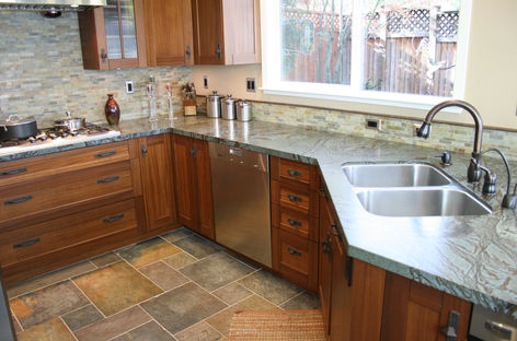 Wooden kitchen with cabinets, dishwasher, sink, and window; modern home interior.