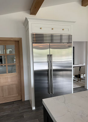 Stainless steel refrigerator in a modern kitchen with a wooden door.