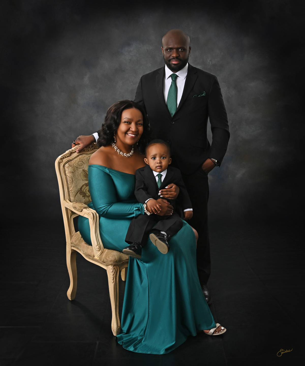 Fine art family portrait of parents and their young son, mother in an emerald gown