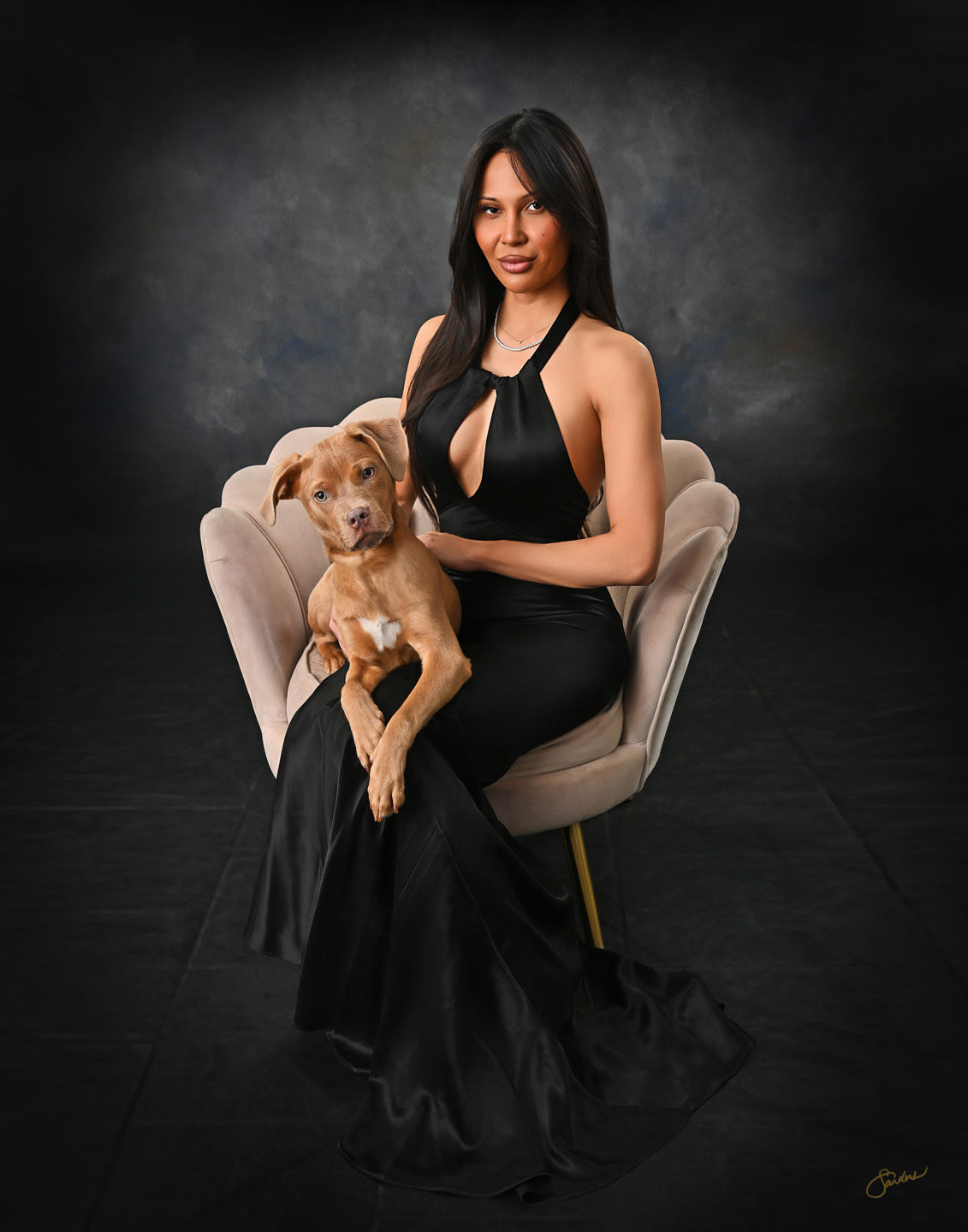 Fine art portrait of a woman in a black gown holding her puppy