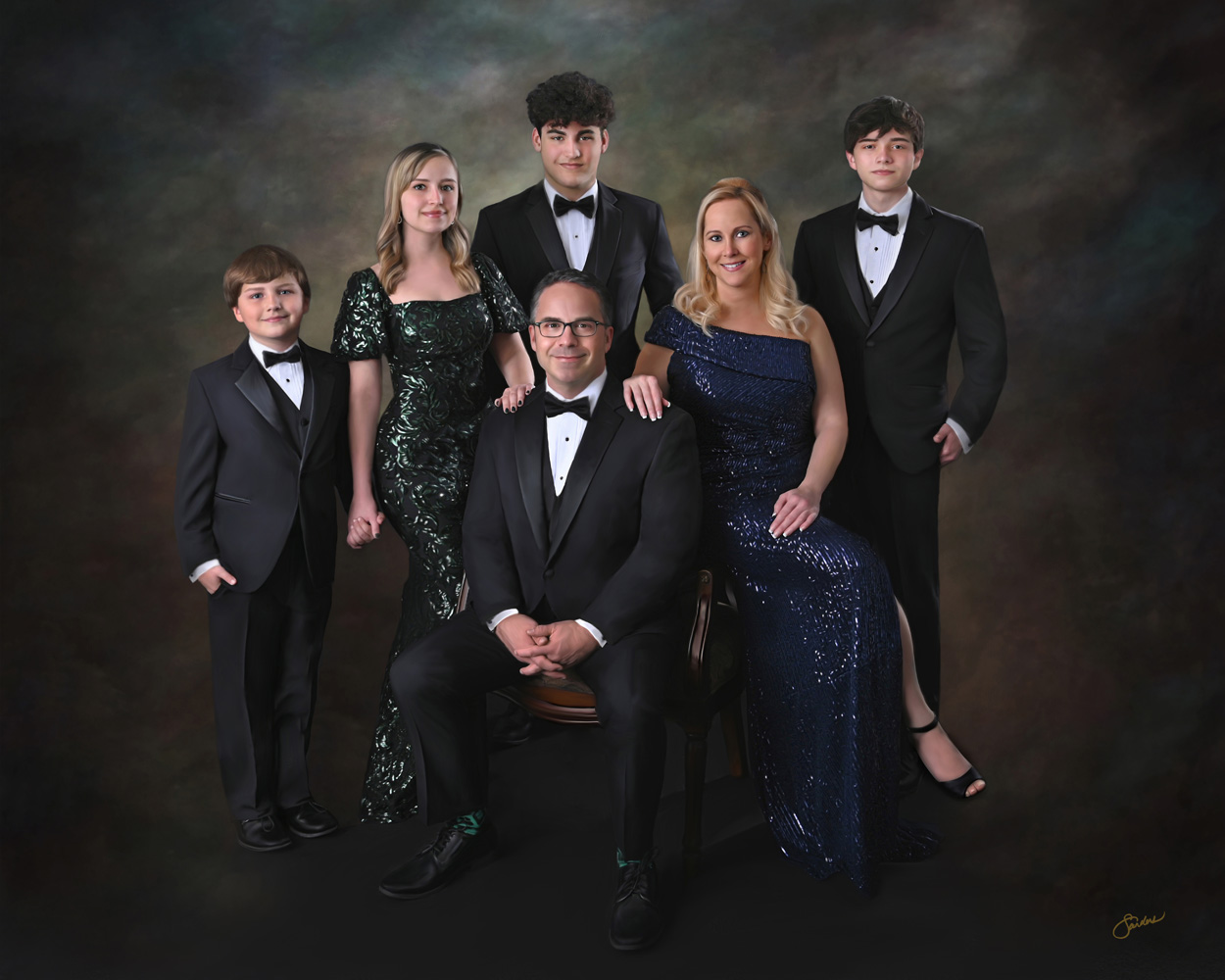 Fine art family portrait of seven in formal black attire with emerald and navy sequin gowns
