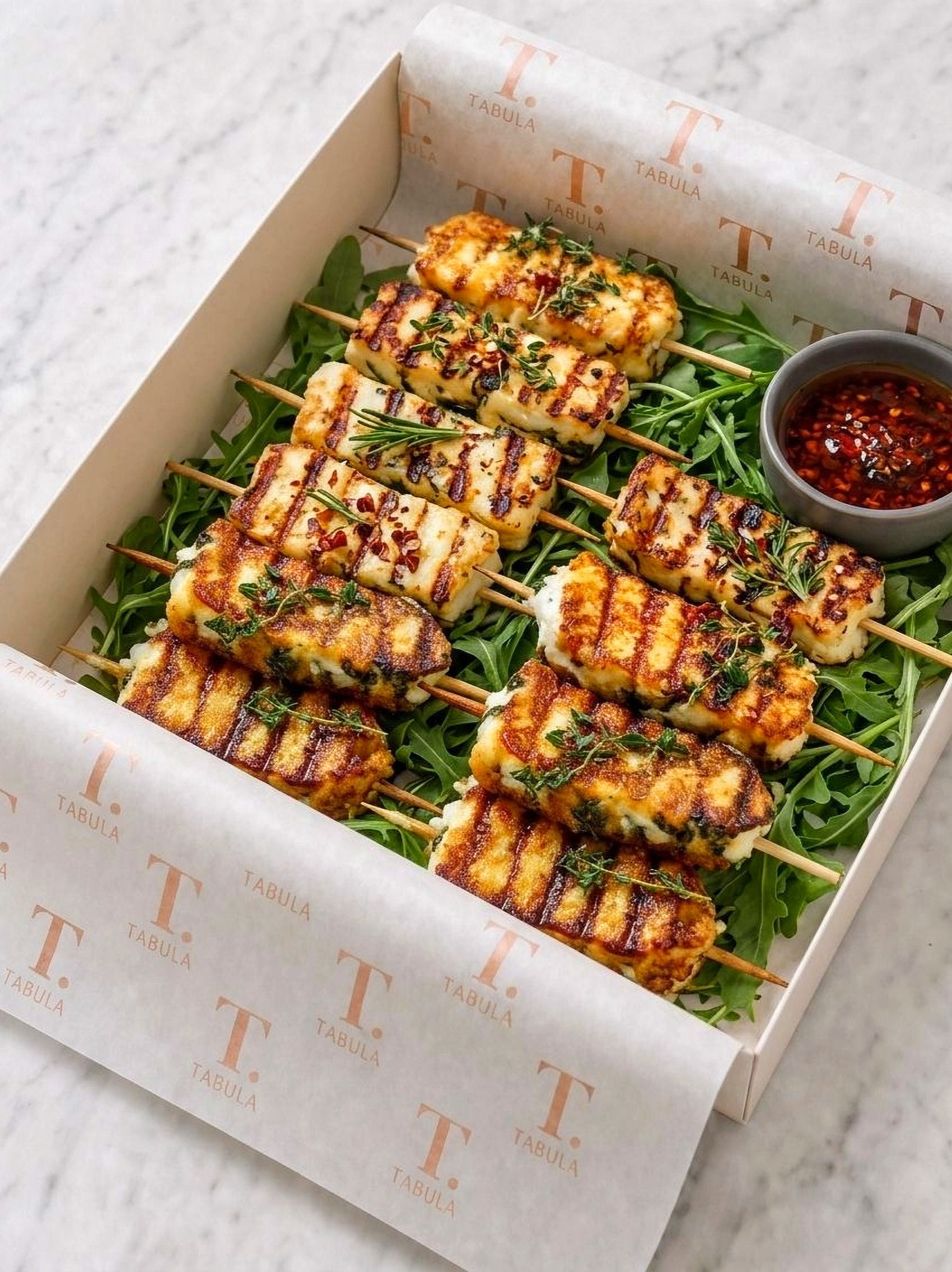 Grilled Halloumi cheese skewers with rocket, herbs and chilli dipping oil