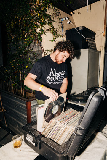 DJ setting the vibe at Baba’s heated backyard event space in Williamsburg, featuring vinyl records for a unique party experience.