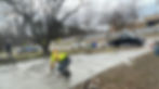 Worker smoothing a newly poured concrete driveway.