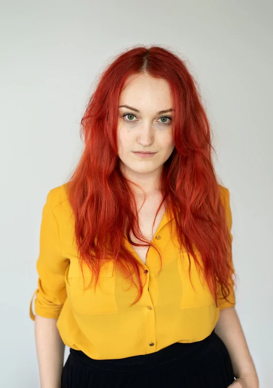 A headshot of Sophia Ralston. Long red hair, yellow top.