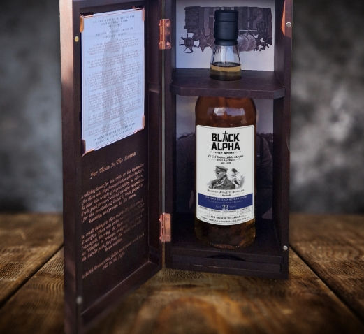 Eye-level view of a bottle of Black Alpha Irish Whiskey on a wooden table with a rustic background