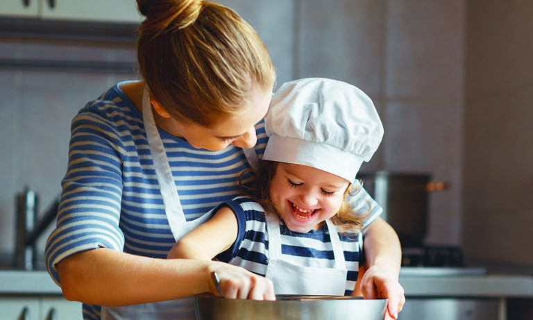 A happy child cooking with her mother