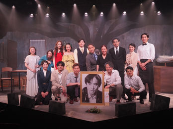 舞台俳優とスタッフ集合写真、ポートレートを囲んで記念撮影、舞台背景、劇団