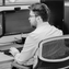 Man working on a multi-monitor computer set-up with BAE Networks' logo.