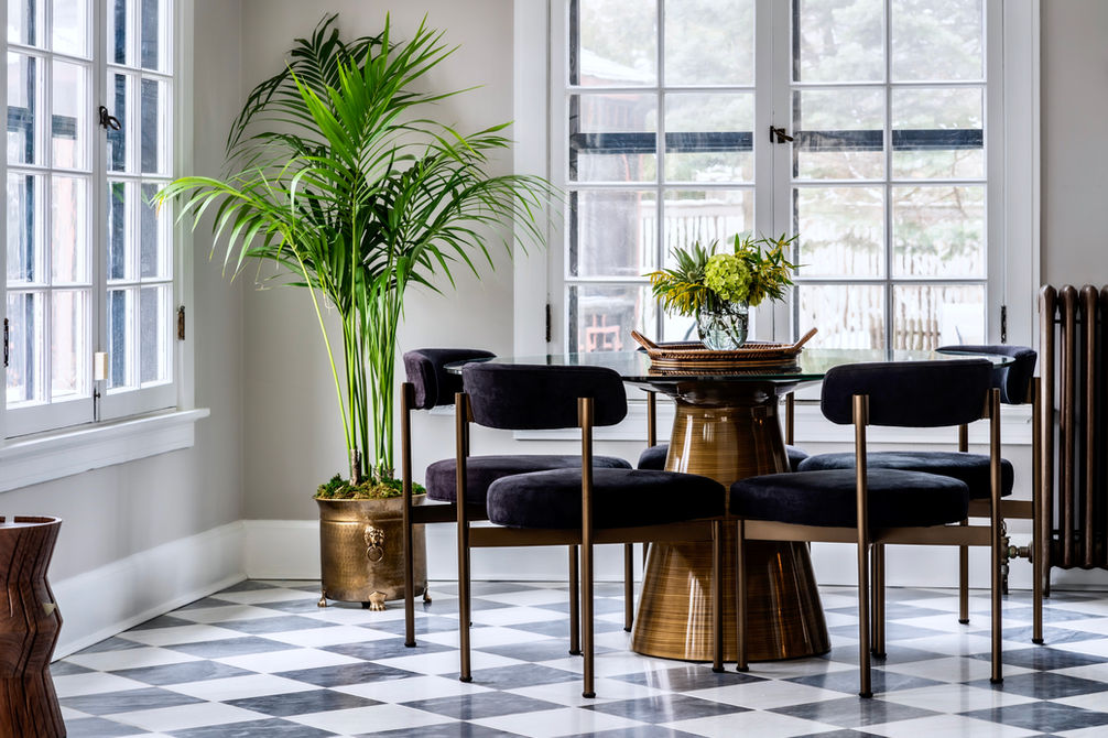 Coffee table room with dark velvet chairs, checkered floor, and green plant decor.