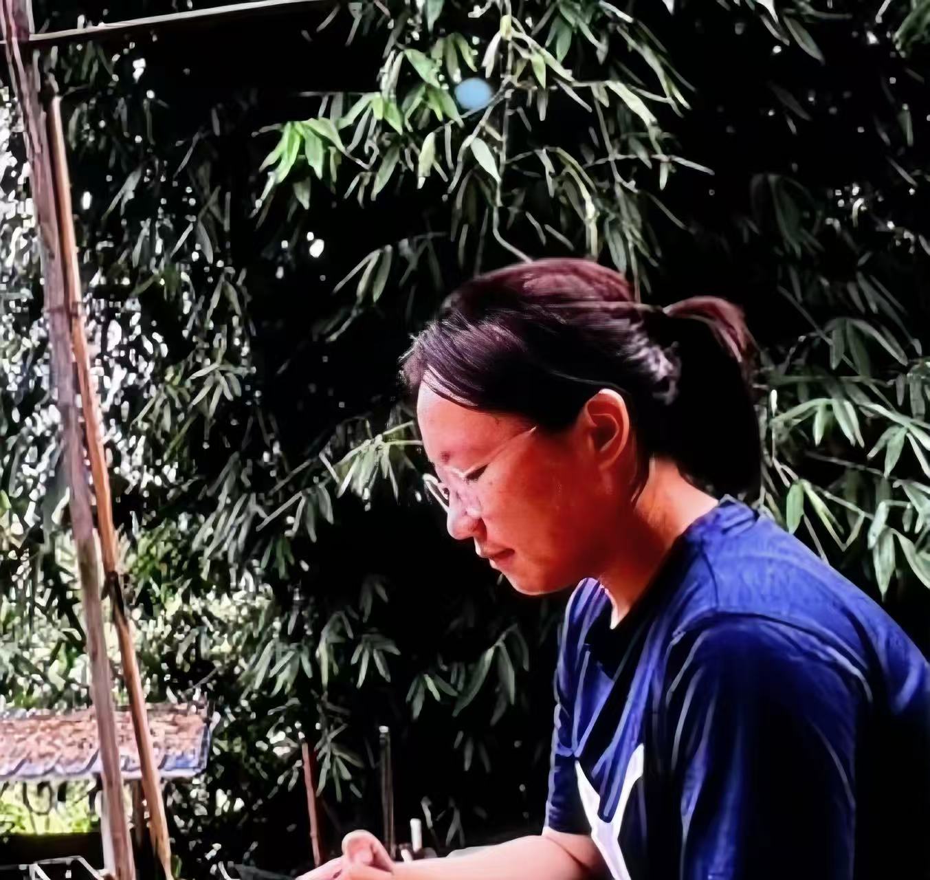 Boge Xiao taking notes during a fieldwork interview, with bamboo behind her.